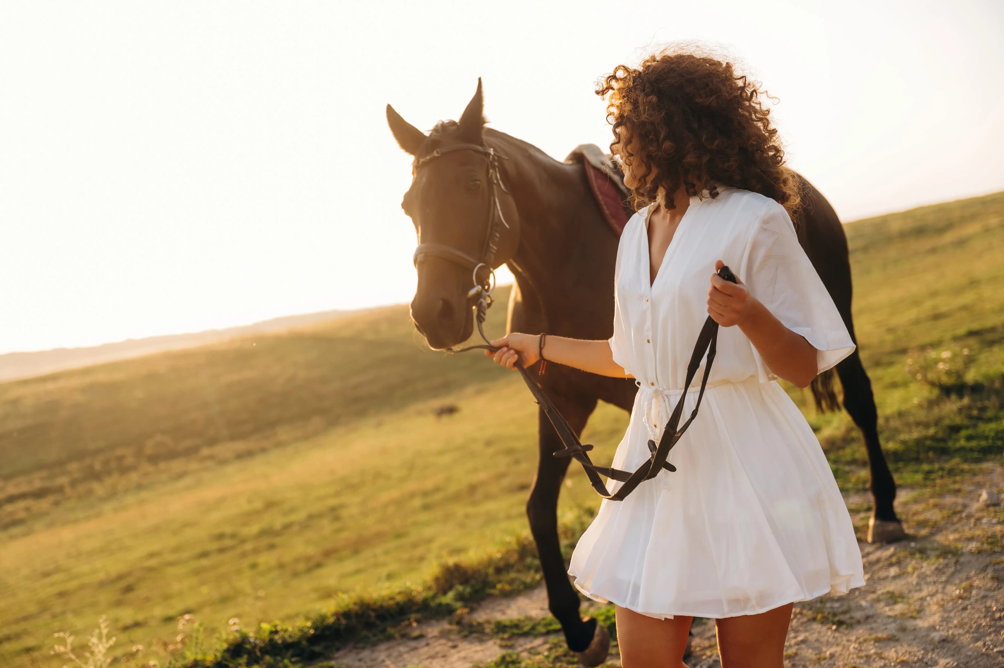 A woman walking beside her horse along a countryside path