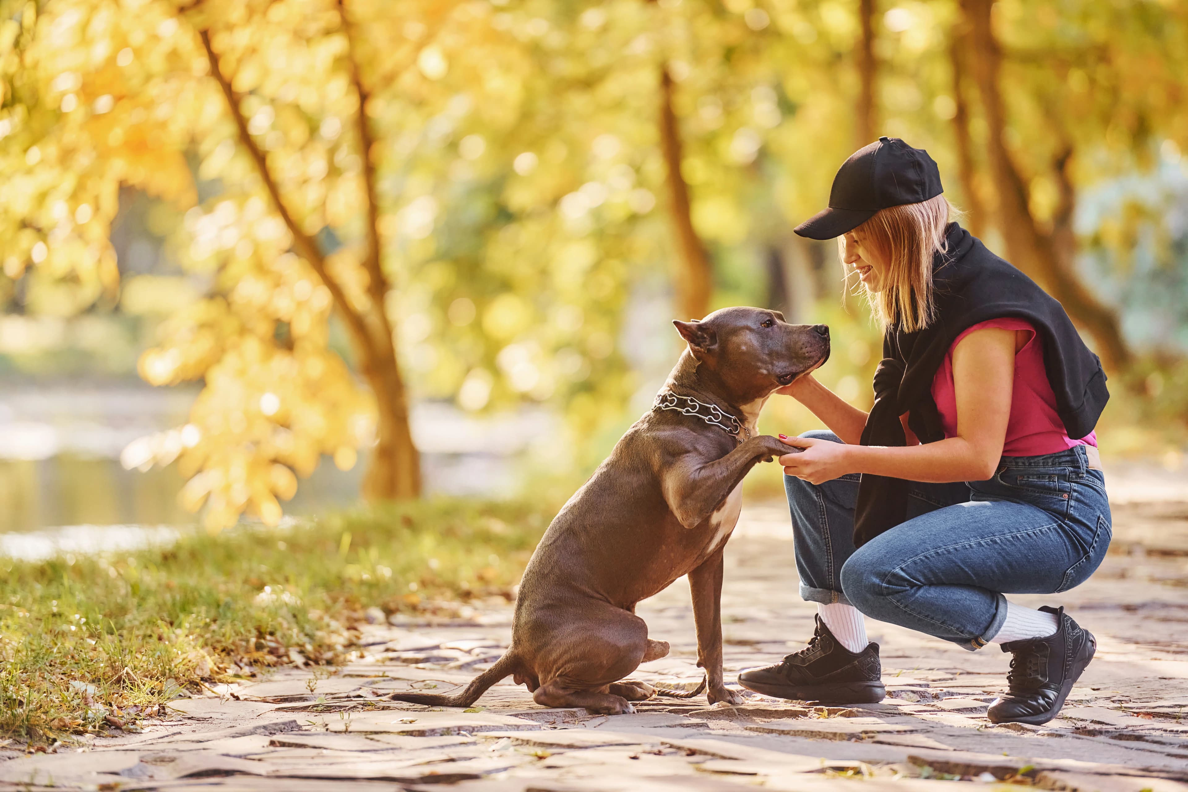 A woman sharing a joyful moment with her dog in an autumn park