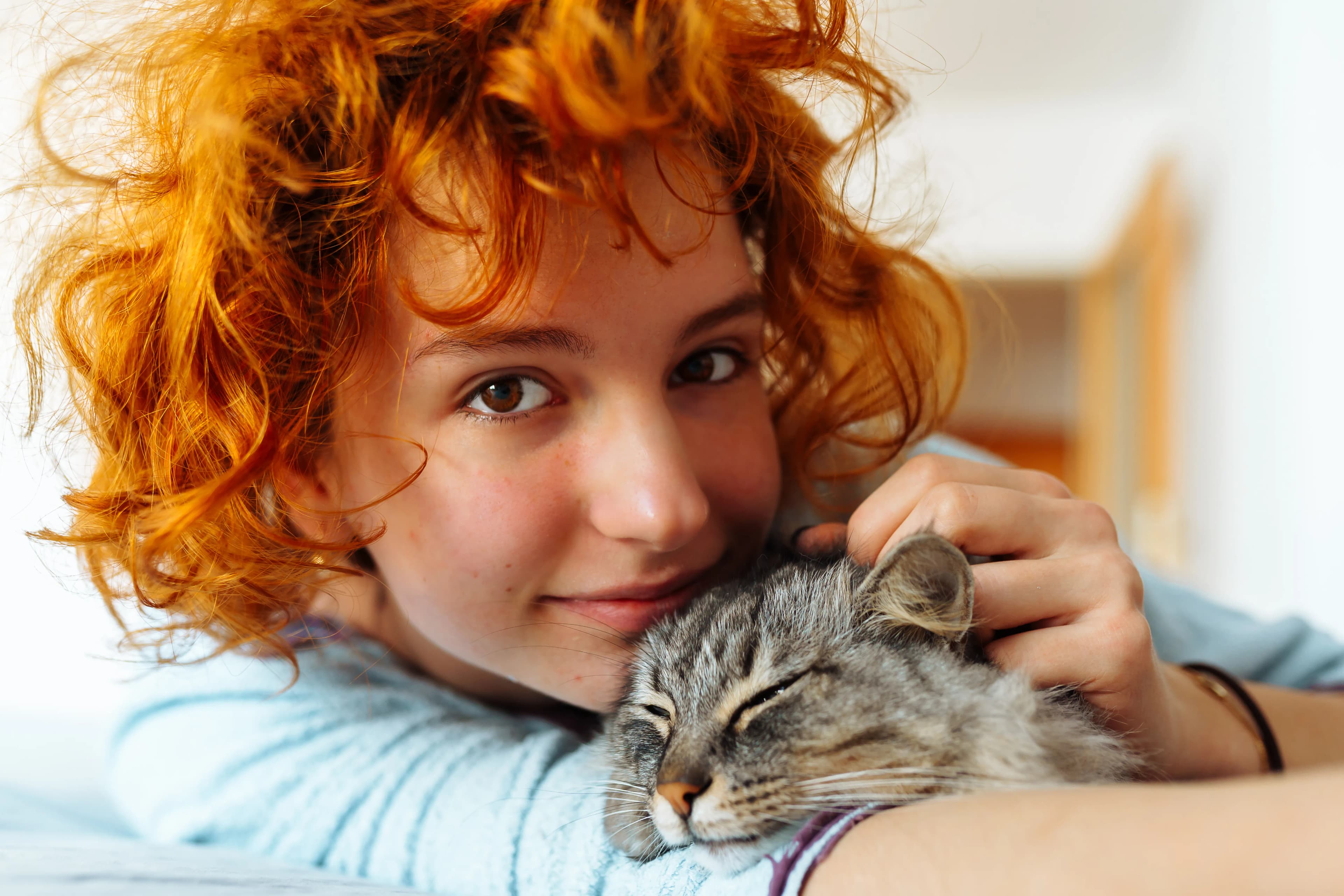 A woman cuddling her relaxed gray tabby cat