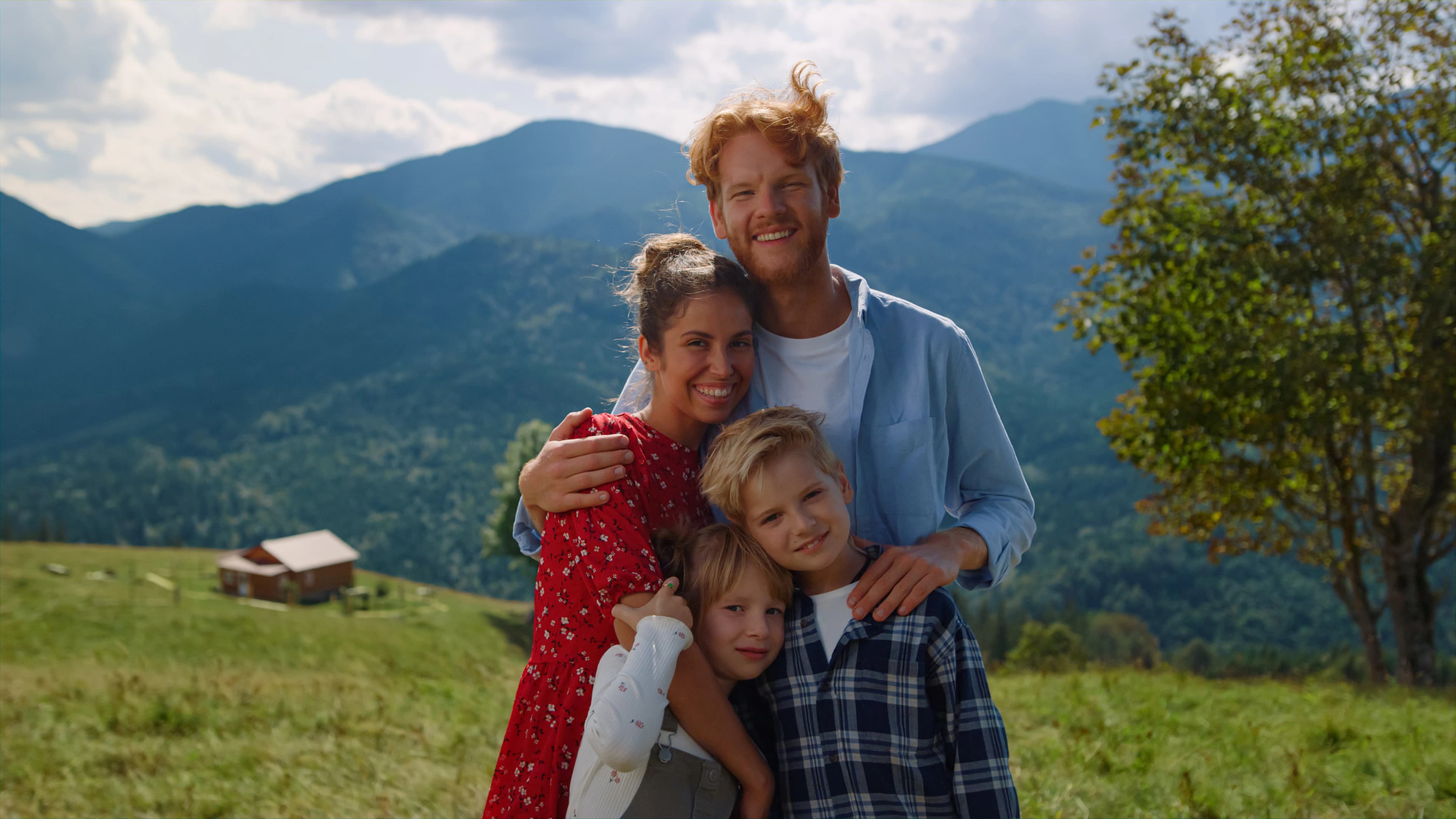A family embracing together with their dog on a mountain hillside
