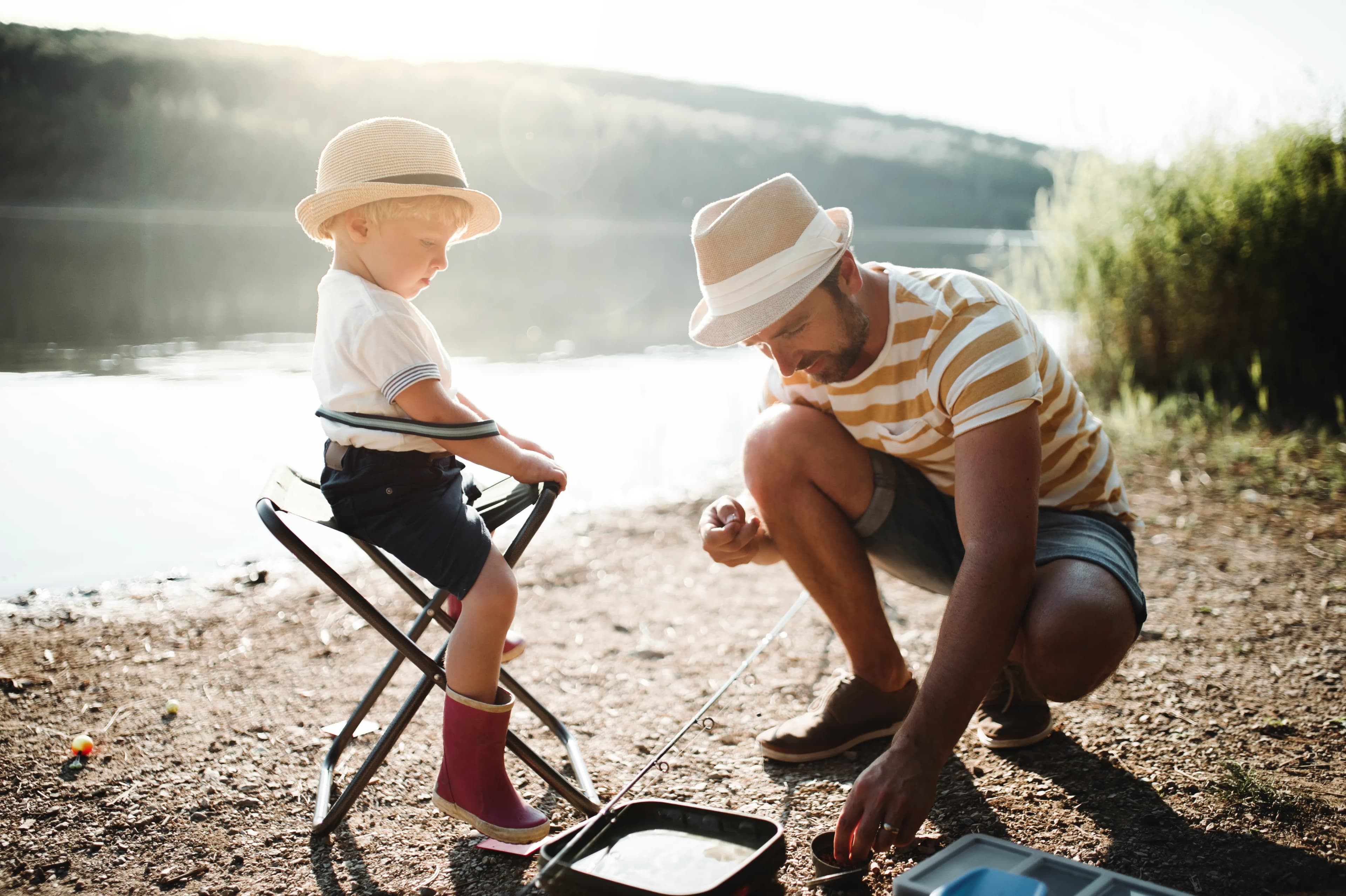 A father teaching his children to fish beside a lake