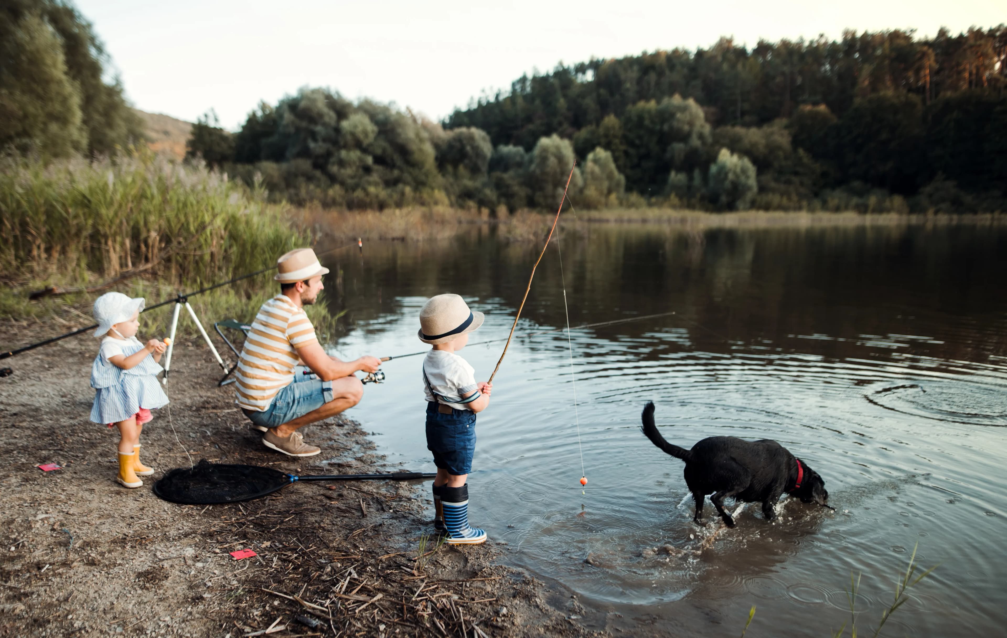A family spending time outdoors with their dog beside the lake