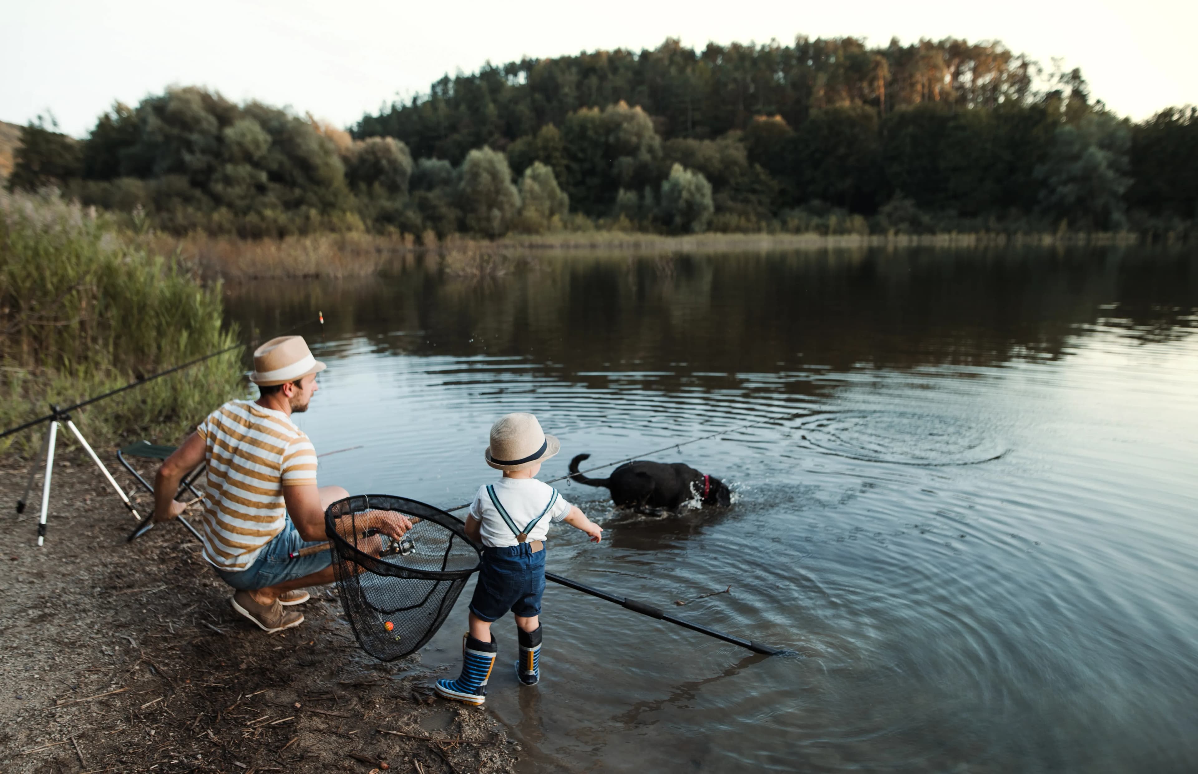 A father, children, and their dog enjoying a day together beside a lake