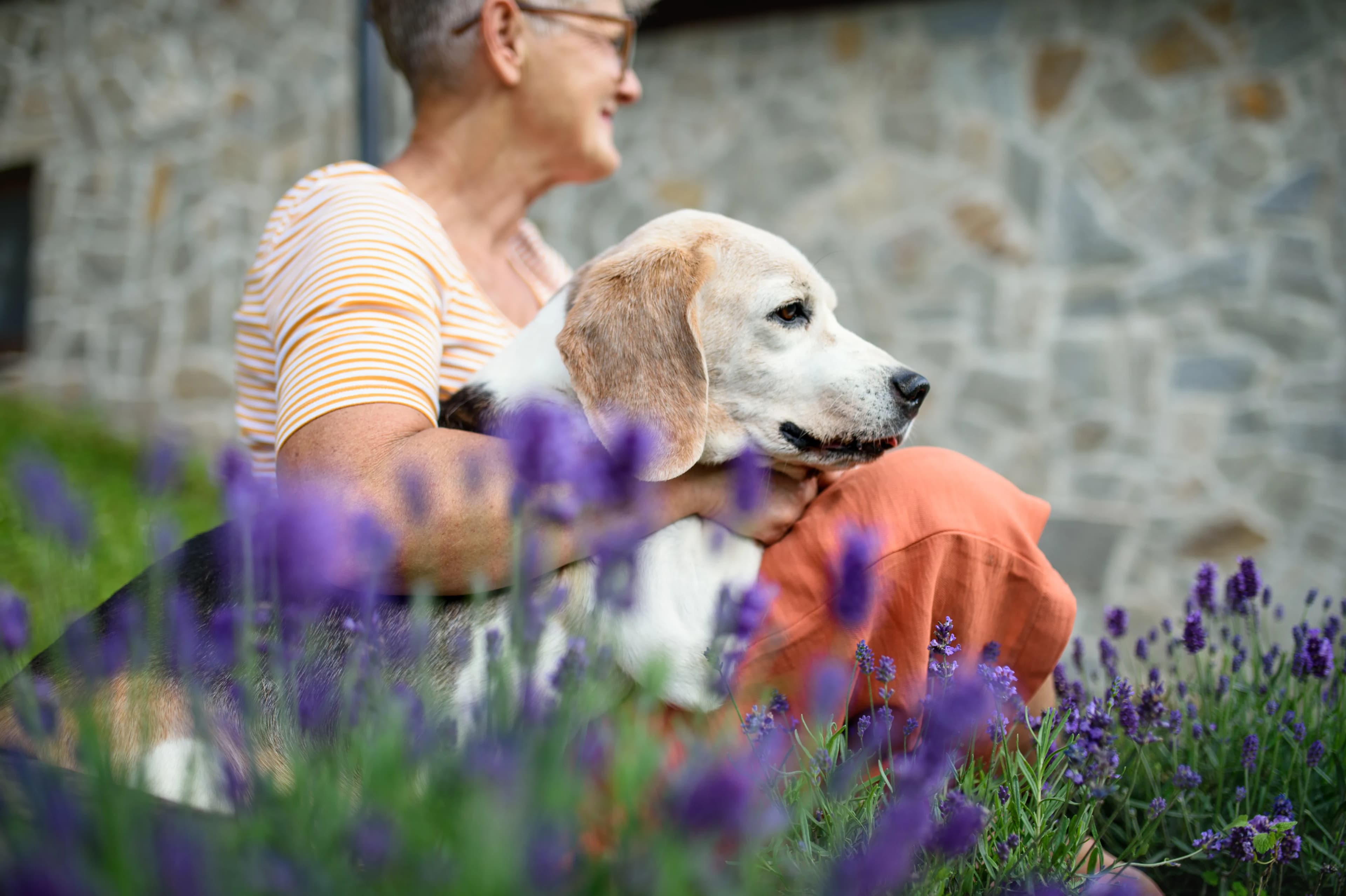 A woman gently embracing her dog outdoors