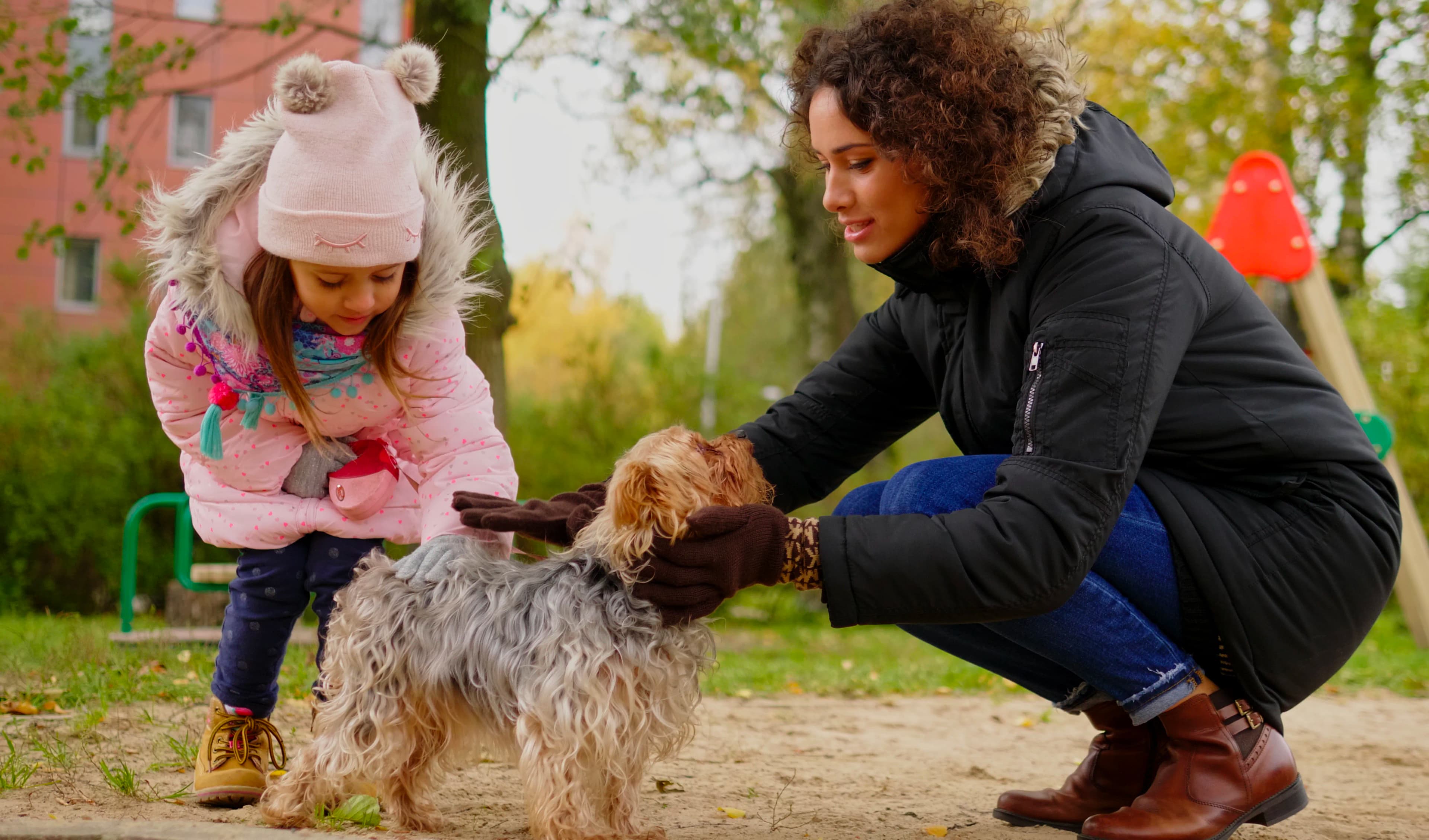 Mother and daughter sharing a quiet moment with their dog during an outdoor family pet photography session