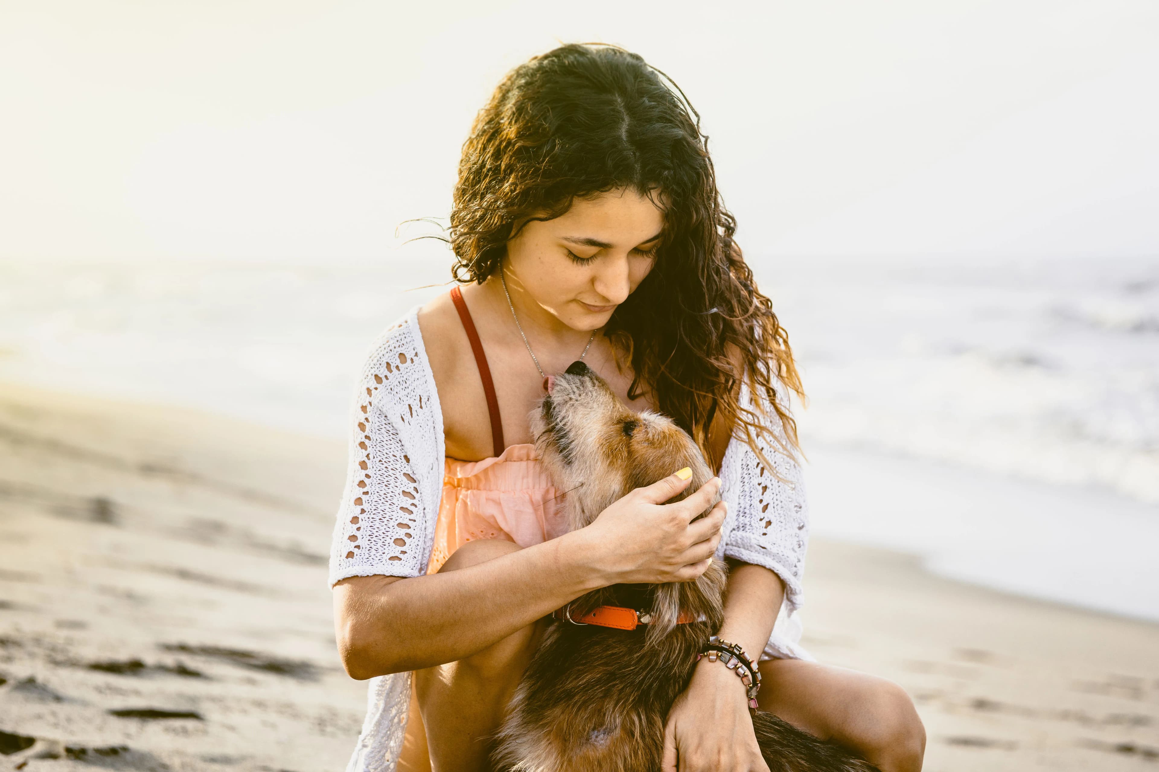 Woman holding her dog close during a beach photography session